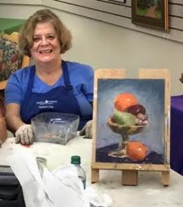 Suzanne Bennett holding one of her pastel paintings of fruit