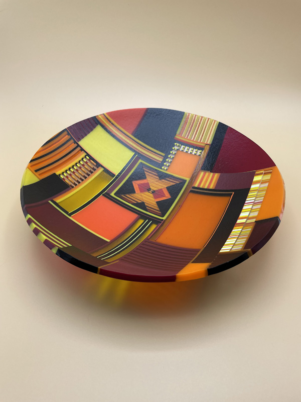 Kiln fired glass bowl in oranges and black, fired in a ball mold with a rounded bottom by Renee Farr