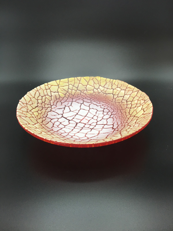 Kiln fired glass bowl in warm colors of red, orange, and yellow. Design is created using glass powder and finished with an organic rim by Renee Farr